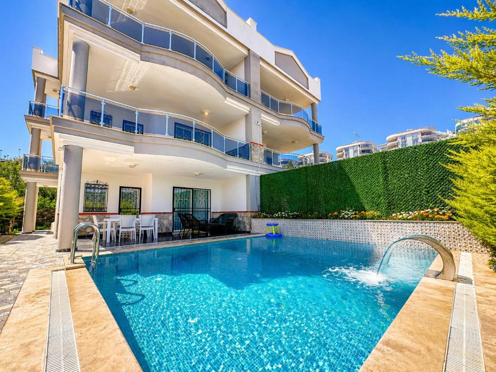 a swimming pool in front of a house at Begonville Villas Ladies Beach in Kuşadası