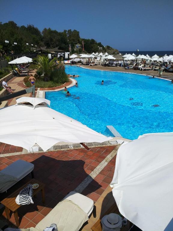 a large swimming pool with blue water and white umbrellas at Oasis Resort&Spa Lozenets Studio 12 in Lozenets