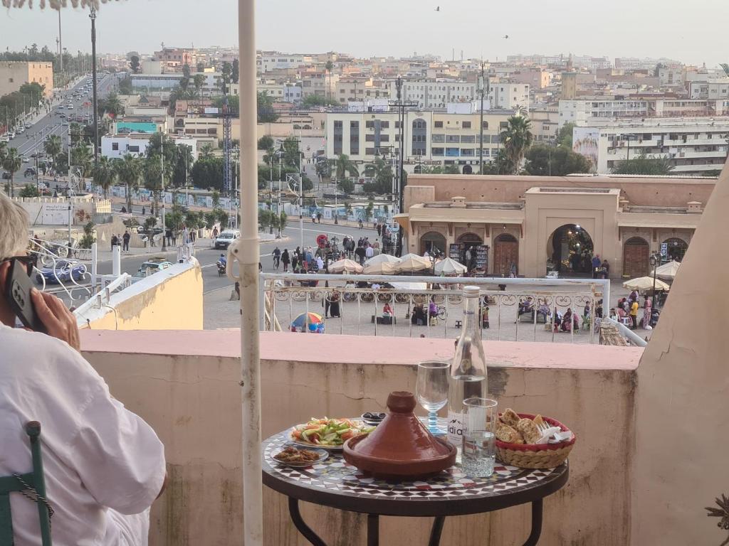 a person sitting on a balcony with a table with food at Riad Felloussia in Meknès