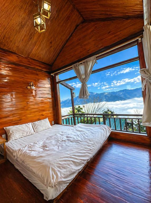 a bedroom with a bed and a large window at Mống Vàng Retreat Tà Xùa in Sơn La