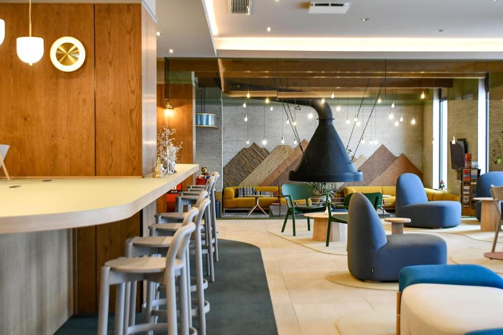 a lobby with a bar with chairs and tables at Hotel Edel Warme in Furano