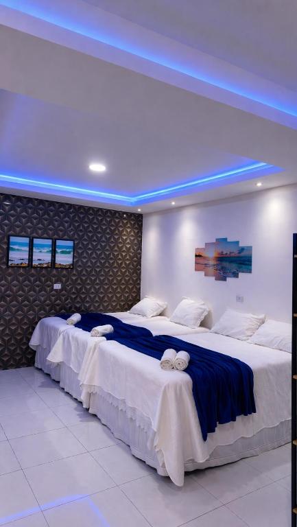 Apartamento Inteligente - 50m da praia في جاباراتينغا: سريران كبيران في غرفة بإضاءة زرقاء