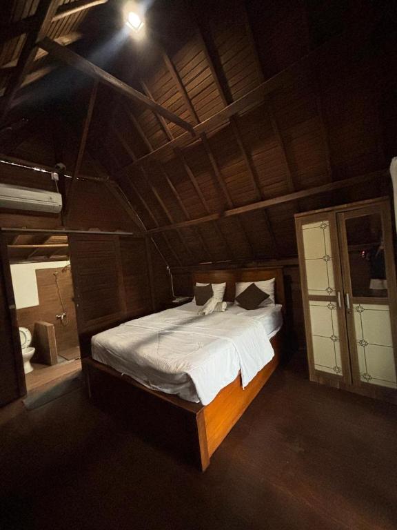a bedroom with a large bed with white sheets and pillows at KRECOG Bungalow in Sampalan