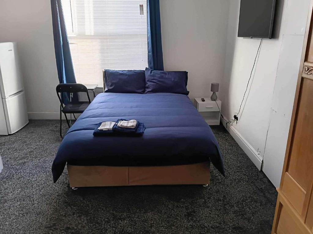 a bedroom with a bed with blue sheets and a tv at Sleeps 2 - Parking - Wifi in Oldbury