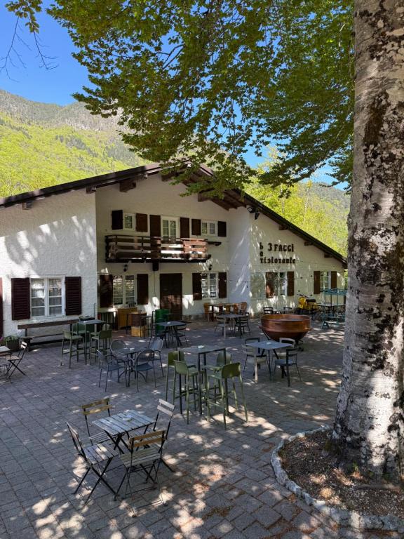a building with chairs and tables and a tree at Al Montel - Tre faggi in Borgo