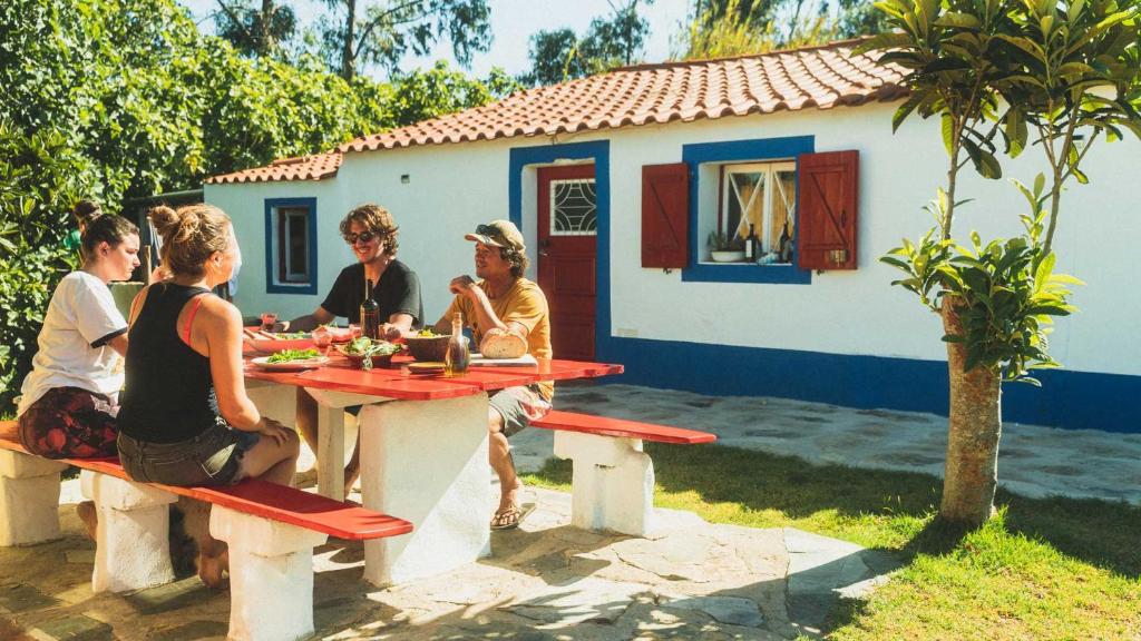 a group of people sitting at a picnic table at Casa no Campo in Porto Covo