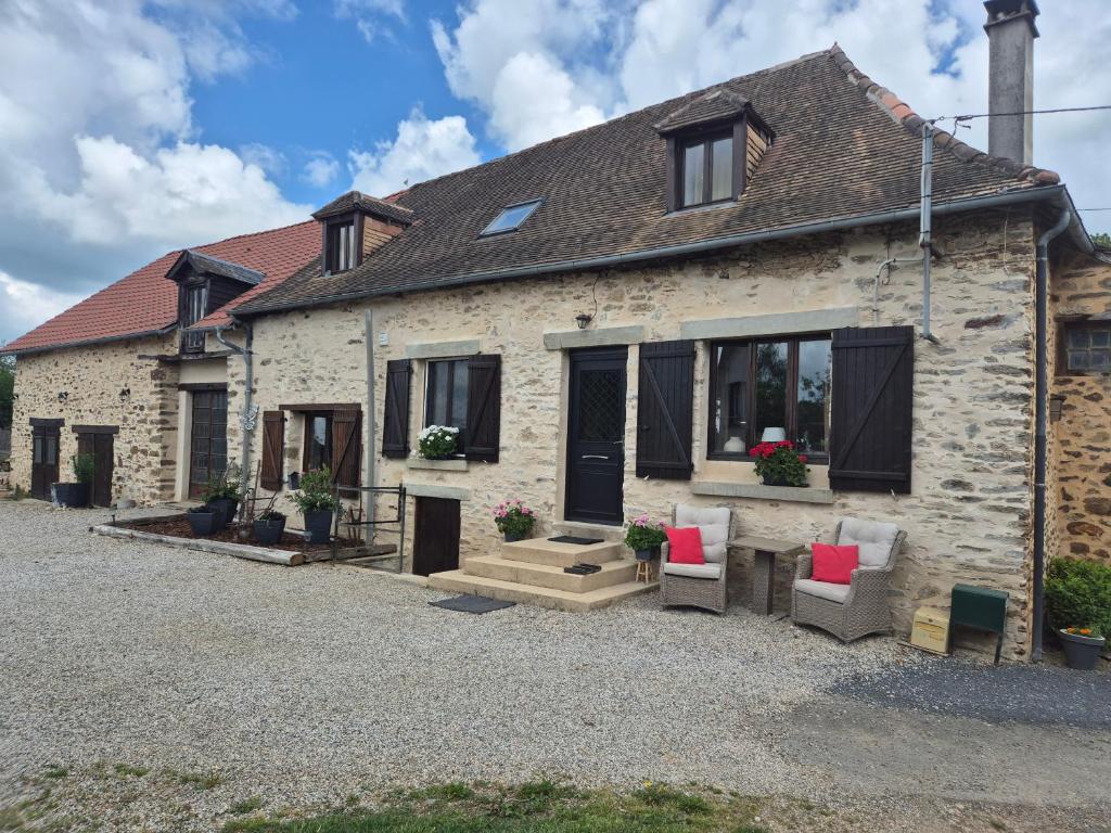 an old stone house with two chairs and windows at Le figuier in Benayes