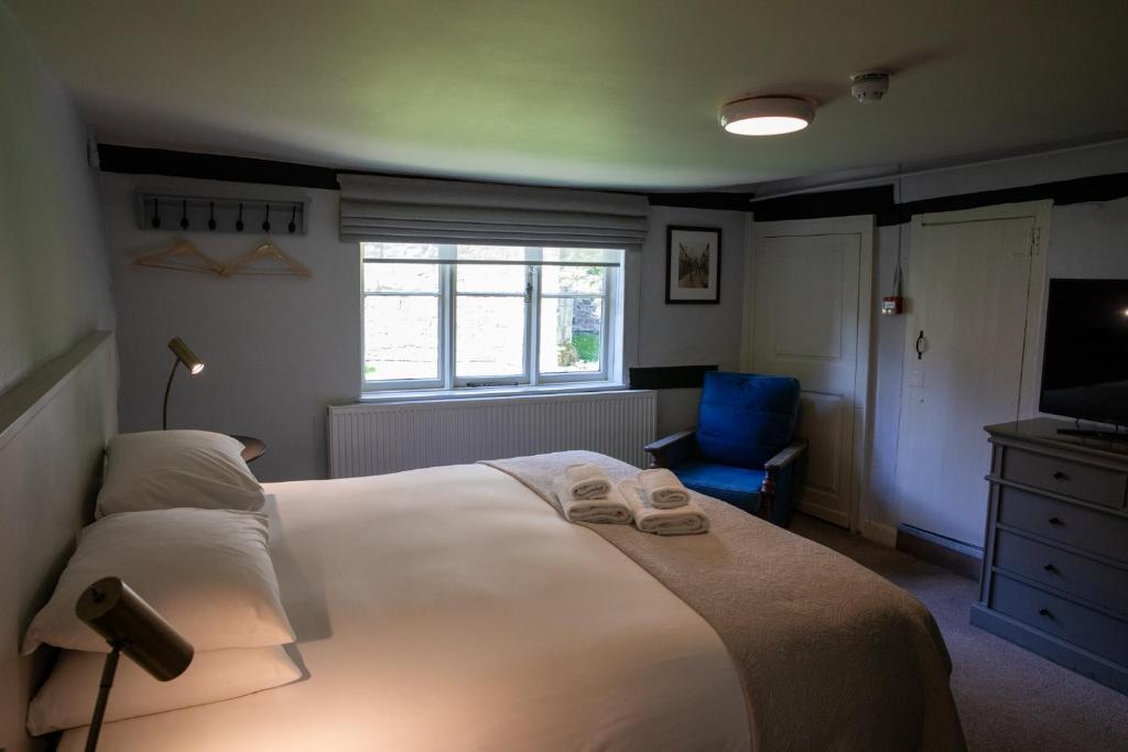 a bedroom with a large bed and a blue chair at The Woolpack Hotel in Tenterden