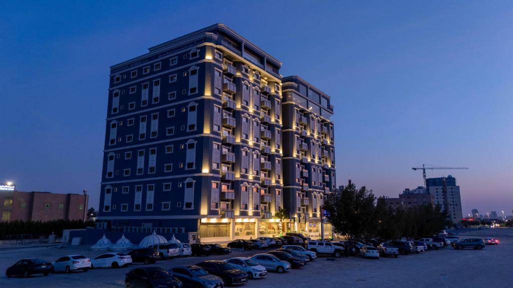 a tall building with cars parked in a parking lot at Corniche Hotel Al Khobar in Al Khobar