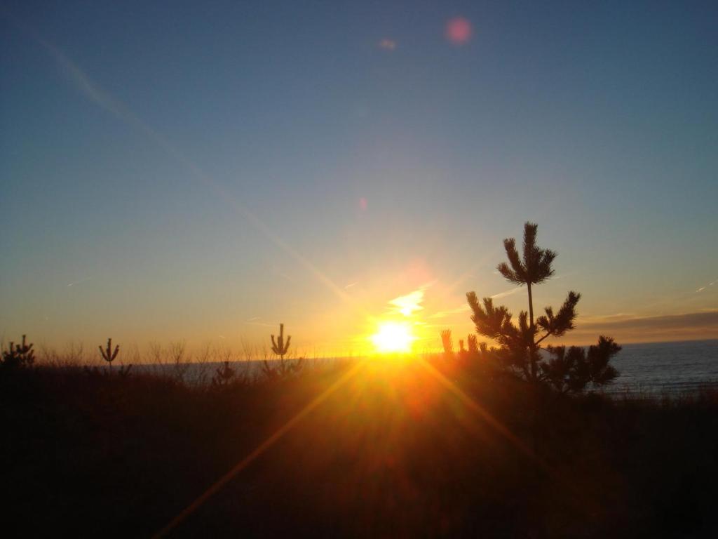 a sunset on the beach with the sun in the sky at Dzintari in Liepāja