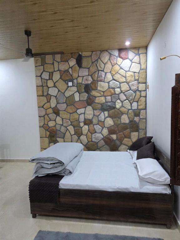 a bed in a room with a stone wall at Ransuli mountain retreat in Dehradun