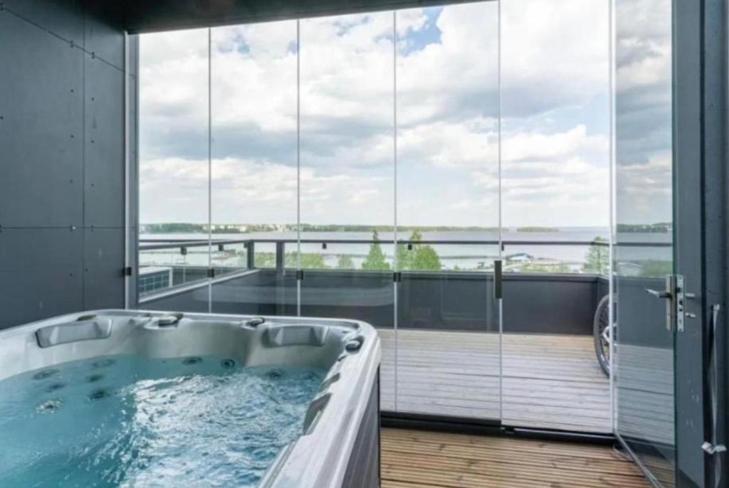 a bath tub in a room with large windows at Luxurious Penthouse - Hot Tub & Sauna in Tampere