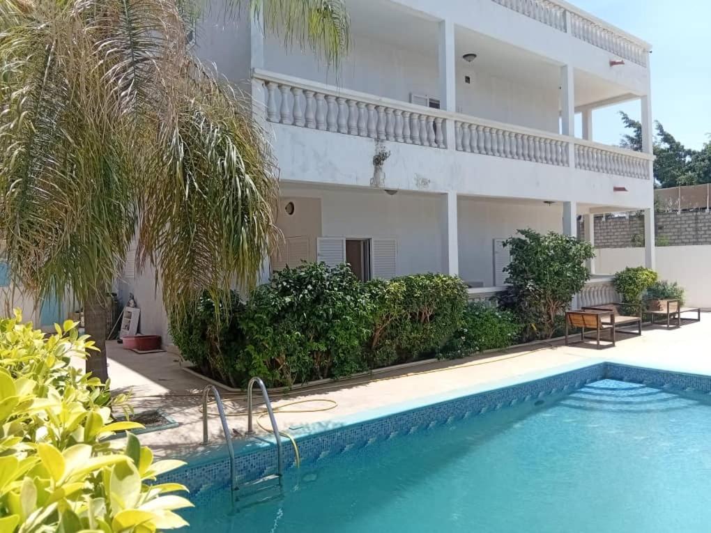 a villa with a swimming pool in front of a building at New White House in Saly Portudal