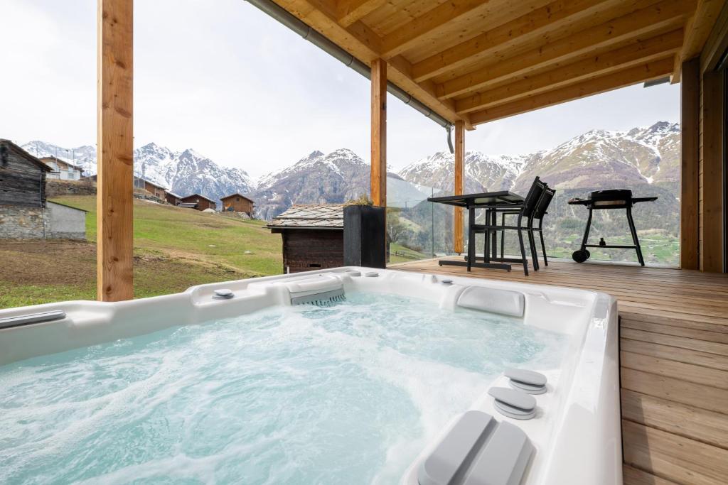 a hot tub on a deck with a view of mountains at Tiny Bishorn mit privatem Whirlpool in Grächen