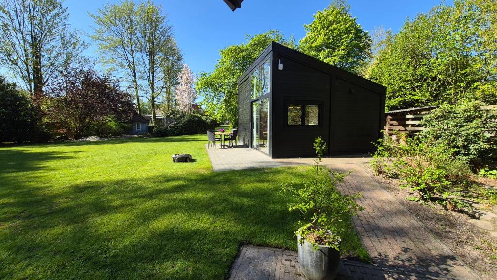 ein schwarzes Haus in einem Garten mit grünem Rasen in der Unterkunft De Kansel in Nieuw-Dordrecht