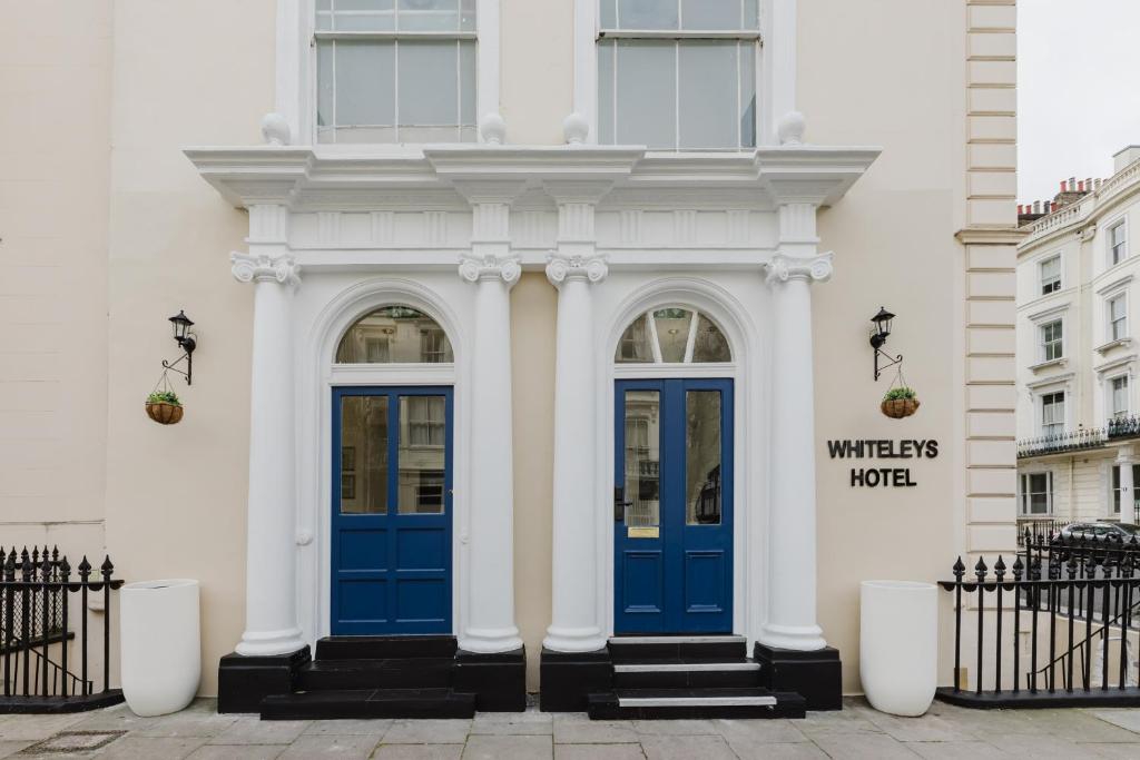 a white building with blue doors on it at Whiteleys Hotel in London