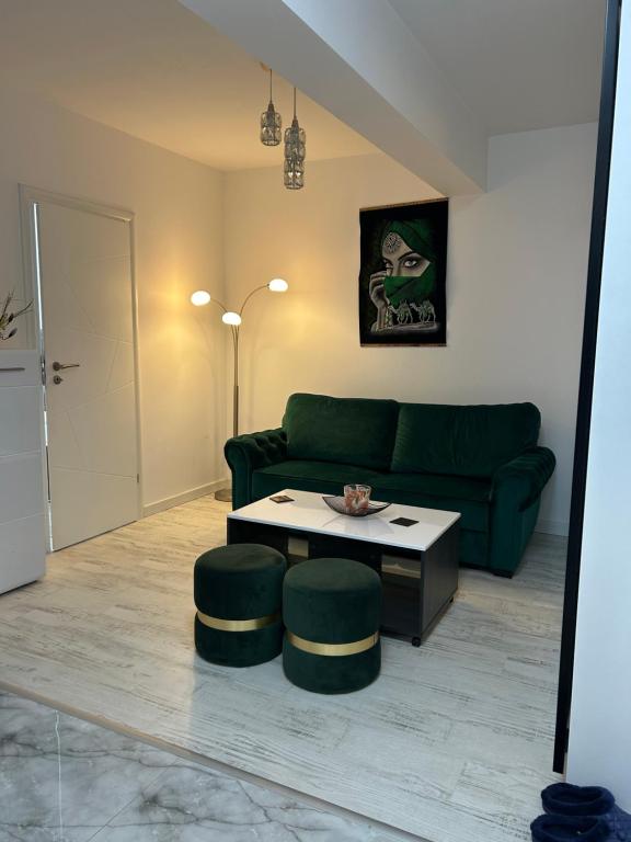 a living room with a green couch and a table at Andra Rezidence in Popeşti-Leordeni
