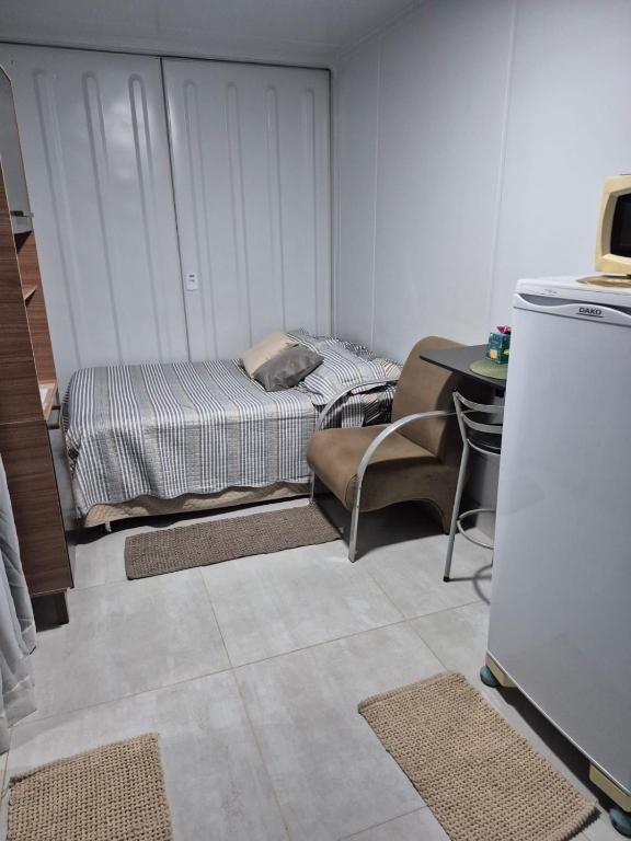 a room with a bed and a chair and a table at Refugio Stella Container - Aconchegante, Completo e Bem Localizado in Brotas