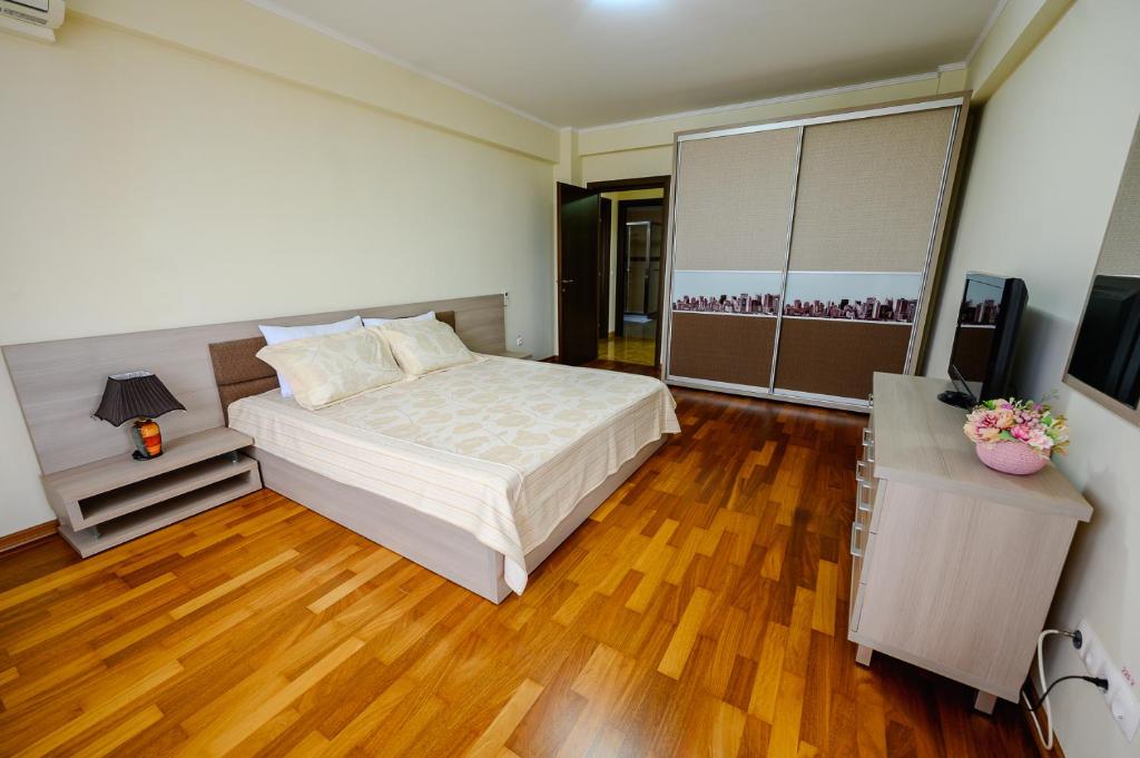 a bedroom with a large bed and a wooden floor at Samali Residence in Eforie Nord