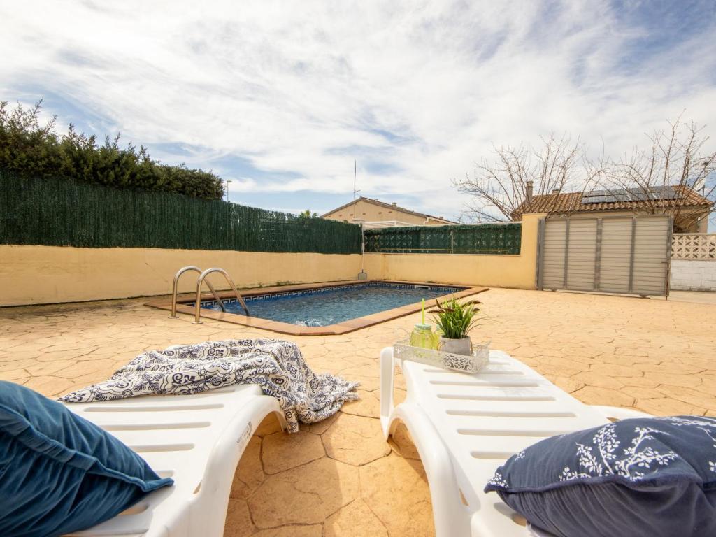 two white benches sitting next to a swimming pool at Holiday Home Flamenc 1 by Interhome in Riumar