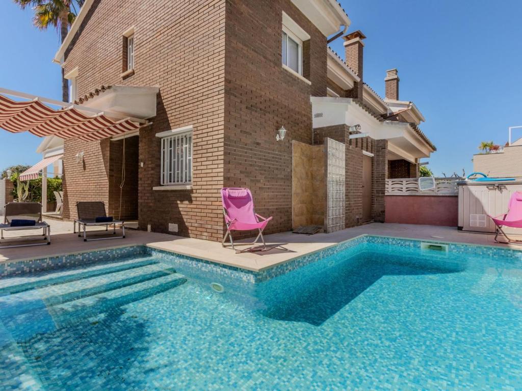 a swimming pool with two chairs and a house at Holiday Home Canyadell by Interhome in Torredembarra