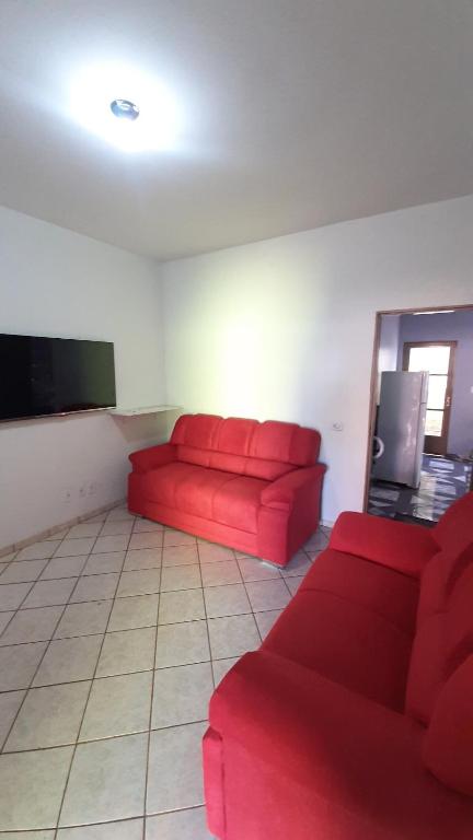 a living room with a red couch and a tv at Casa ampla central in Dourados
