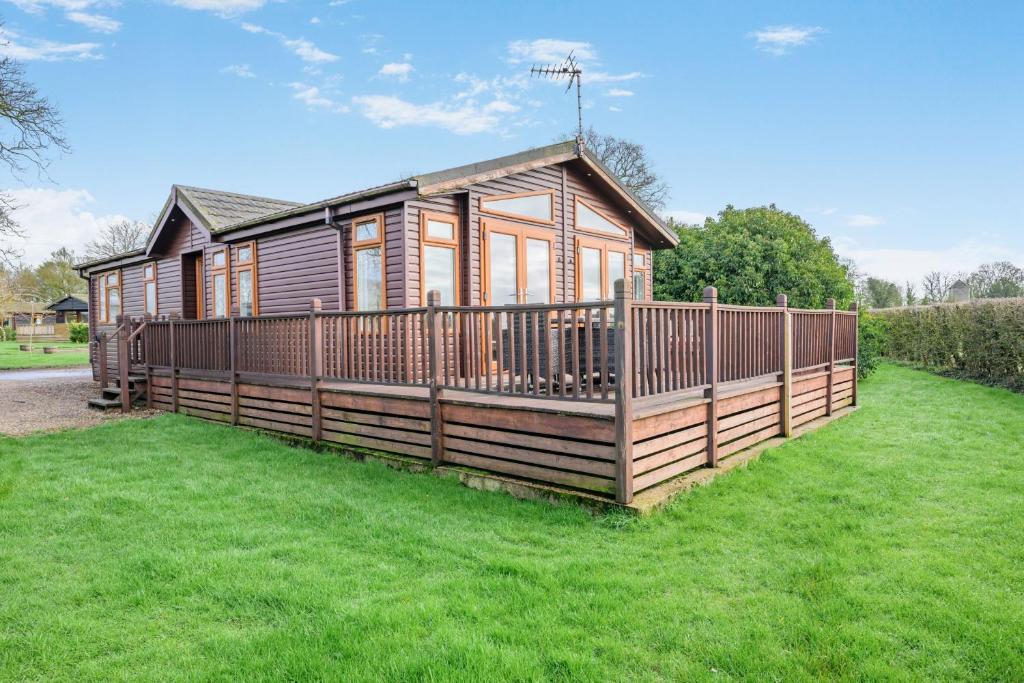 a wooden cabin with a fence in the grass at Field View 2 bed - Hazel in Eye