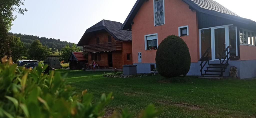 a house with a grass yard in front of it at Holiday Home Vuković Plitvice Mountain Retreat in Saborsko