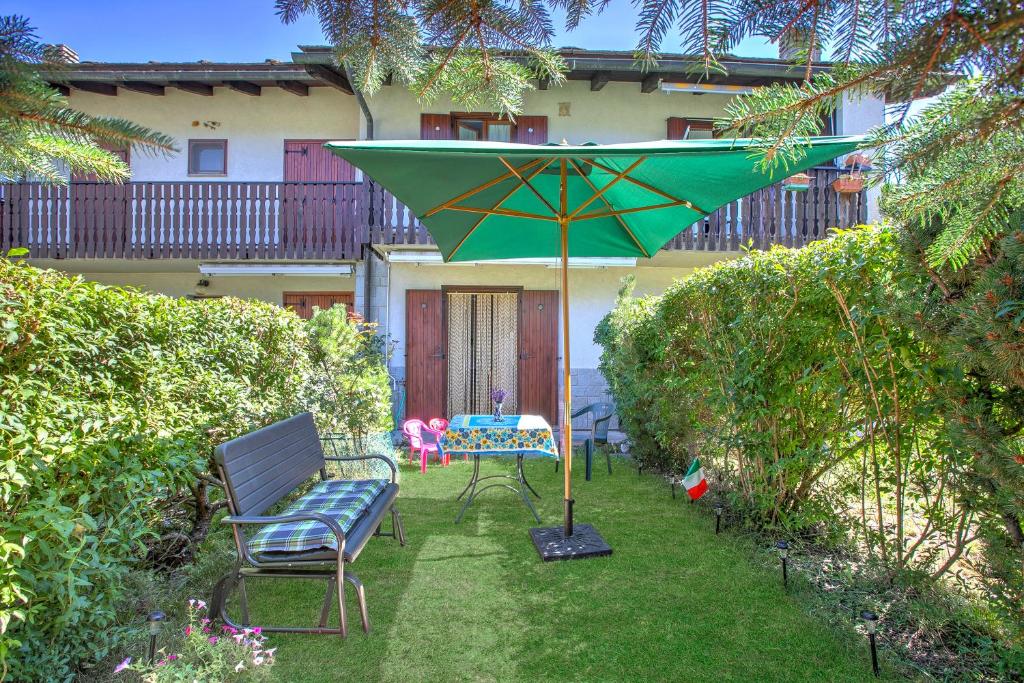 a patio with two chairs and a green umbrella at Maison Rosamunda - Happy Rentals in Oulx