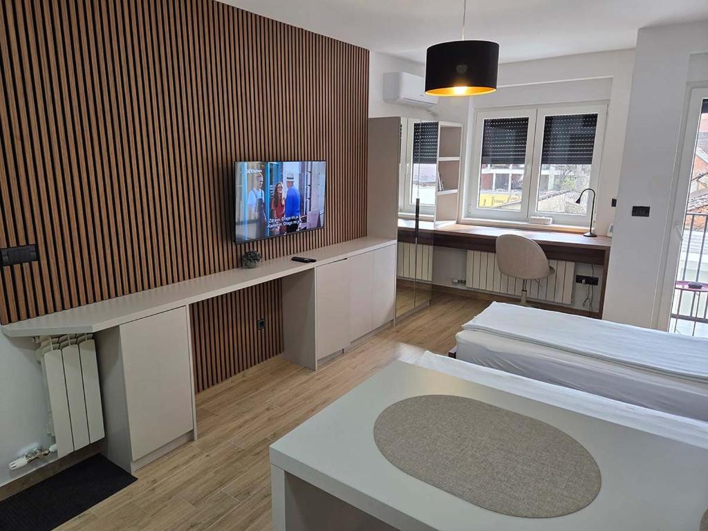 a room with a bed and a tv on a wall at Apartmani Optimist in Valjevo