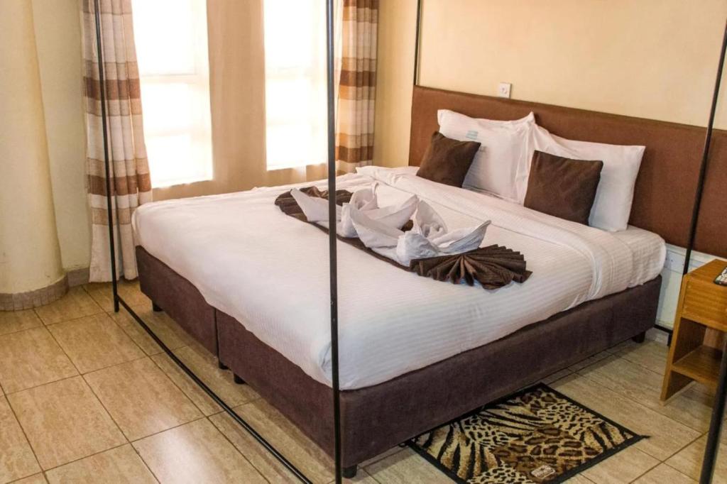 a bedroom with a large bed with white sheets at Greenvale Hotel 1BR Along Kamiti Road in Kiambu
