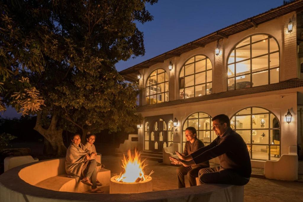 a group of people sitting around a fire pit at StayVista's Casa Blanca - Modern elegance with a pool, spacious lawn & diverse activities in Karjat