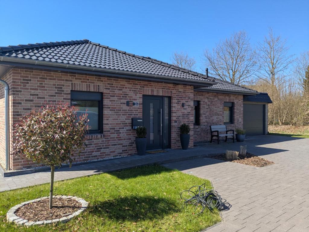 a small brick house with a tree in the yard at Bungalow HWW am Feldrand Ideal für Feriengäste und Handwerker in Wentorf