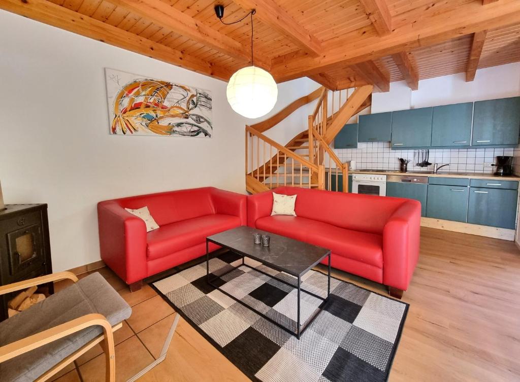 a living room with two red couches and a table at Haus 11 Außergewöhnlich schön gelegen Natur Ferienpark im Teutoburger Wald in Nieheim
