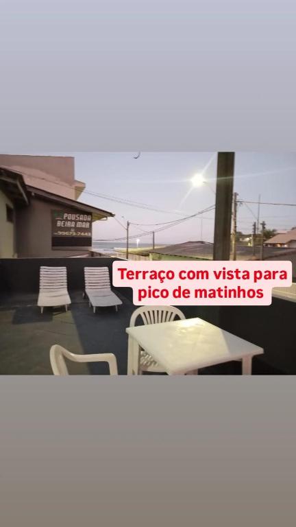 a sign for a patio with chairs and a table at Pousada Beira Mar in Matinhos