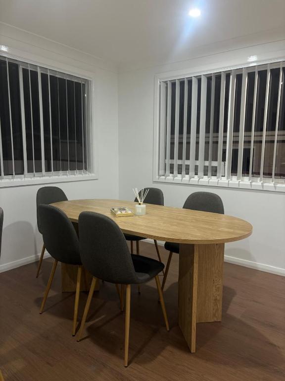 a wooden table and chairs in a room with windows at Second Home - A modern 4 Bedrooms House in Blacktown