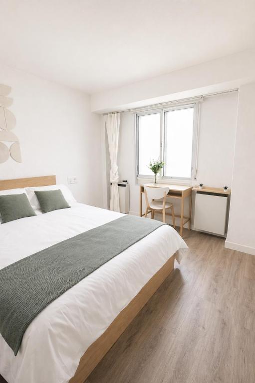a white bedroom with a large bed and a desk at Letras del Tormes in Salamanca