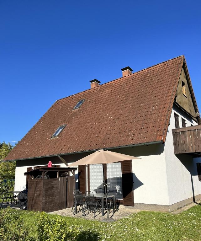 a large white house with a table and an umbrella at Ferienwohnungen Wagner am Brombachsee in Pleinfeld