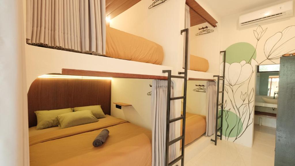two bunk beds in a room with a bedroom at Nira Hostel Kuta Lombok in Kuta Lombok