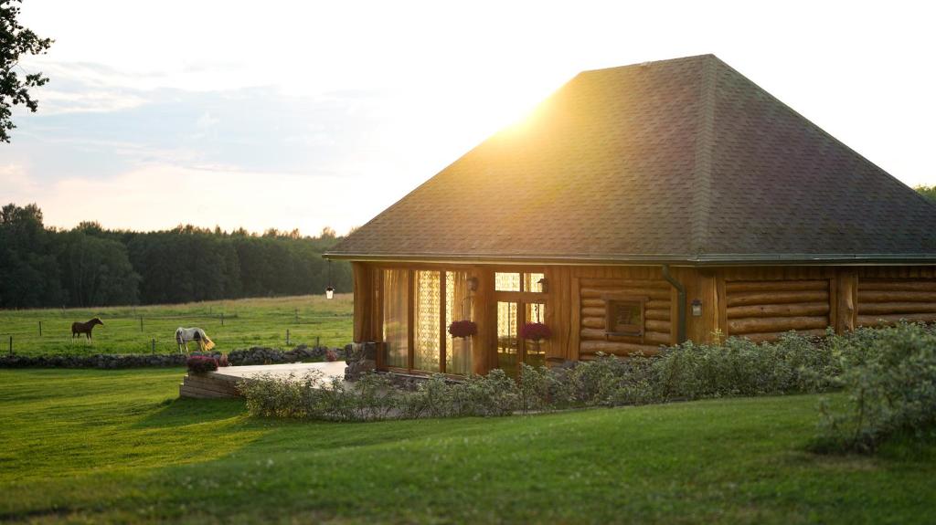 a wooden cabin in a field with a horse in the background at Metsapiiga Talu in Vilina