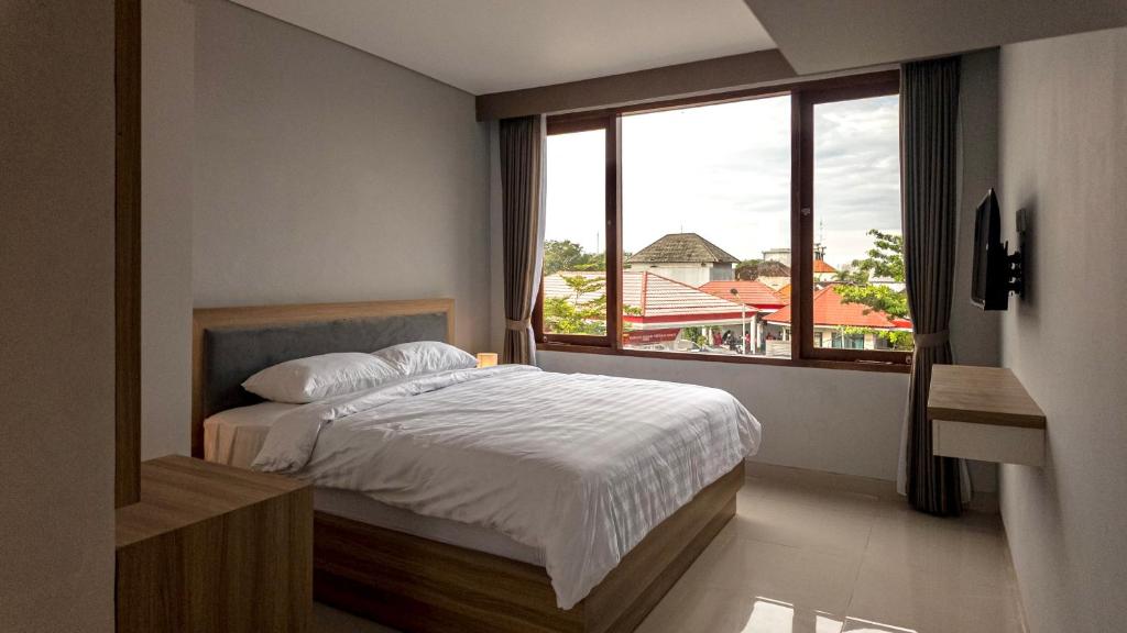 a bedroom with a bed and a large window at Patera Living in Sempidi