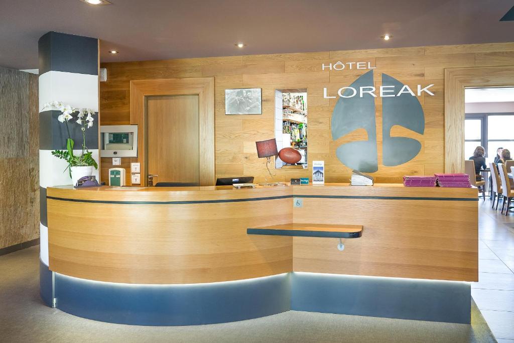 a hotel lobby with a large wooden reception desk at Hotel Loreak in Bayonne