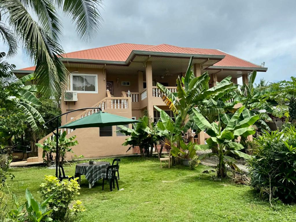 a house with a table and a green umbrella at Bananaland Cottages in Panglao Island