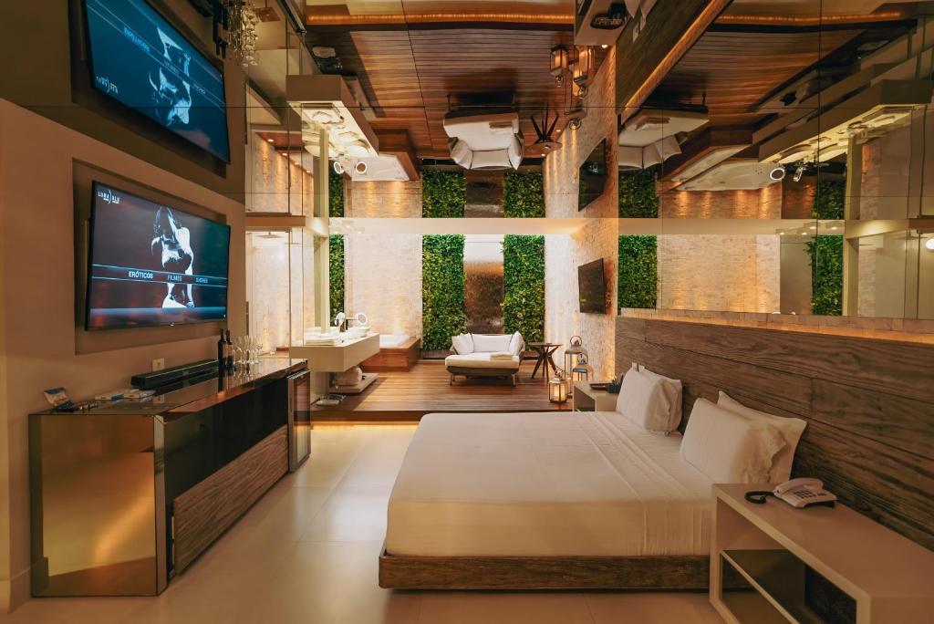 a bedroom with a bed and a tv and a bathroom at Luna Blu Concept in Curitiba