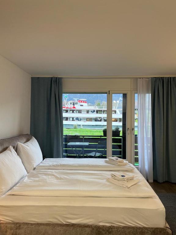 a bedroom with a large white bed with a balcony at Rawda Ferien Wohnung in Interlaken