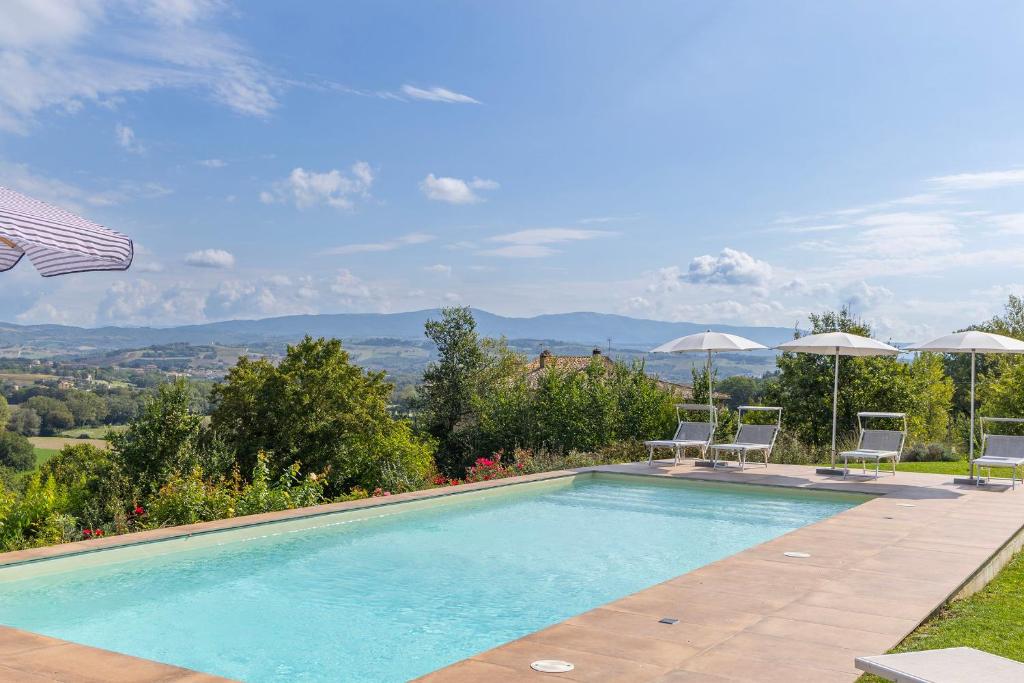 a swimming pool with two chairs and umbrellas at Villa Alessandra in Todi
