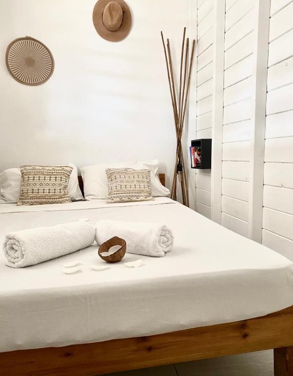 a white bedroom with a bed with a hat on it at Emeraude tropicale in Goyave