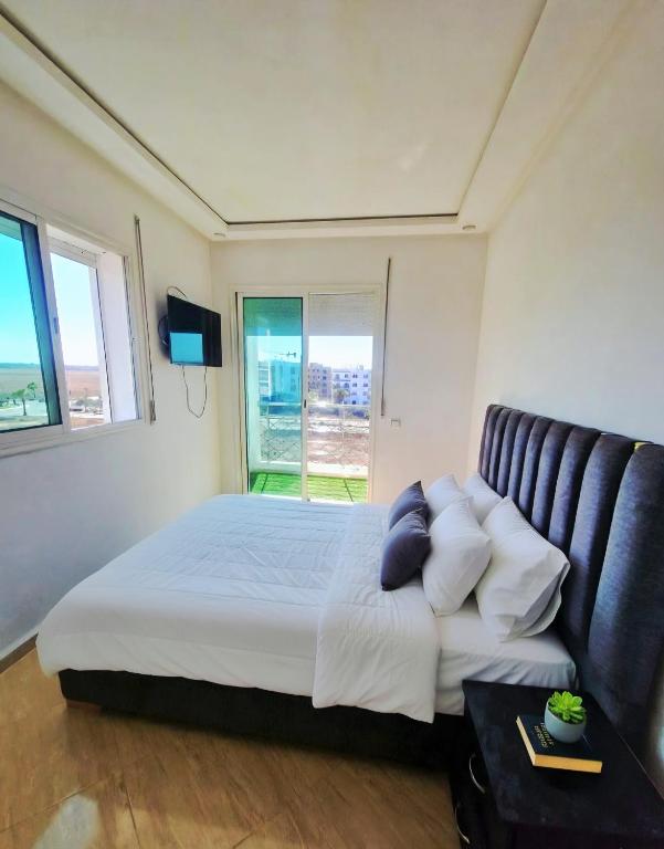 a bedroom with a bed and a large window at APPARTEMENT DE LUXE 3 Façades in Ben Slimane