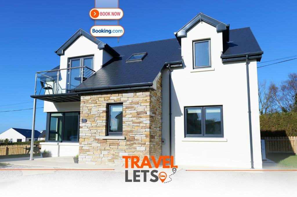 a white house with a black roof at 4 Bedroom House By Travel Lets Holiday Homes Portsalon With Sea View in Portsalon