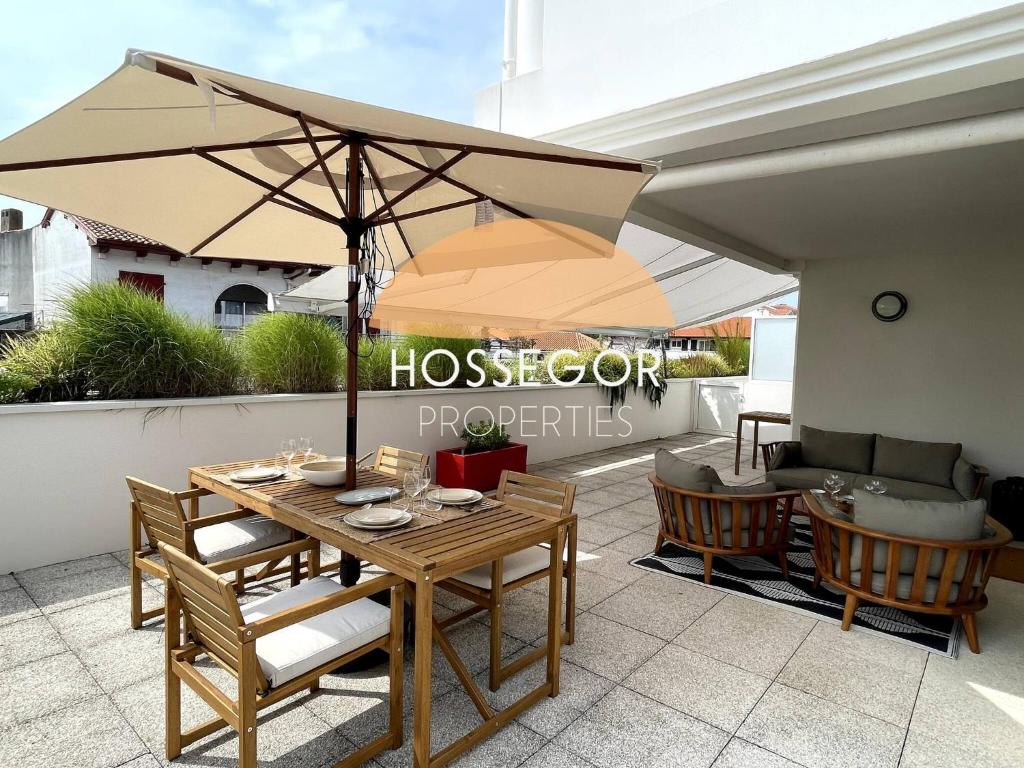 a wooden table with an umbrella on a patio at Le Clos Brémontier in Soorts-Hossegor